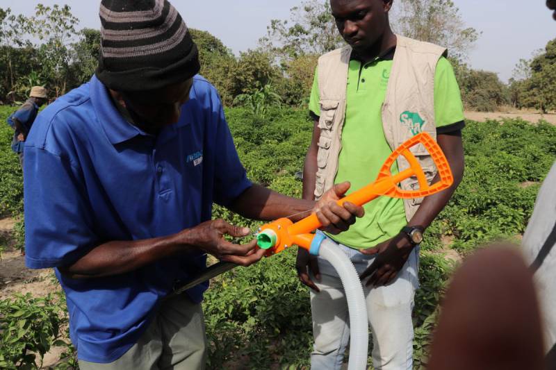 The RA team demonstrates the assembly and use of fertilizer applicators, with farmers actively practicing how to mount the equipment.